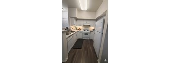 A kitchen with white cabinets and a white fridge.