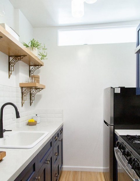 A kitchen with a black refrigerator and a white sink.