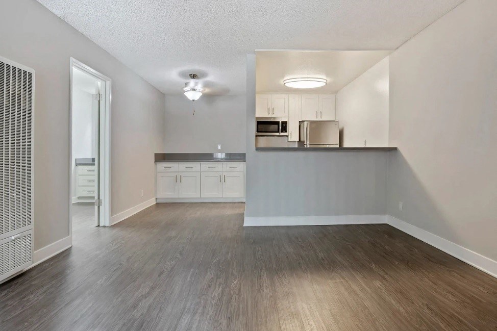 an empty living room and kitchen with wood flooring