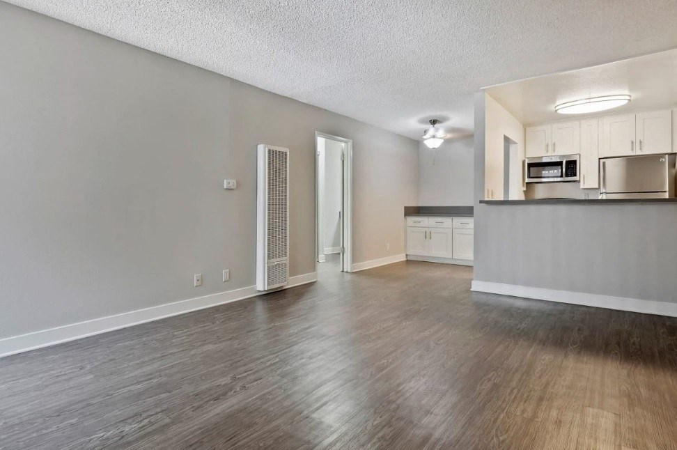 an empty living room and kitchen with wood flooring