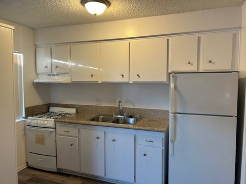 A kitchen with white cabinets and appliances.