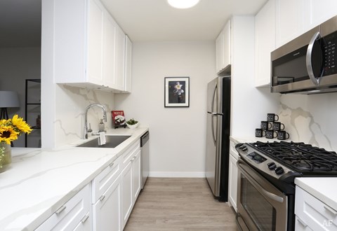 A kitchen with white cabinets and a fridge.
