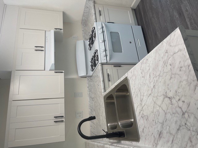 A kitchen with a marble countertop and white cabinets.