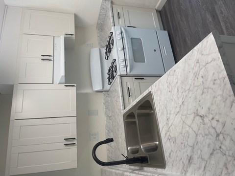 A kitchen with a marble countertop and white cabinets.