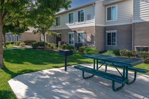A green picnic table is in front of a building with a mailbox.