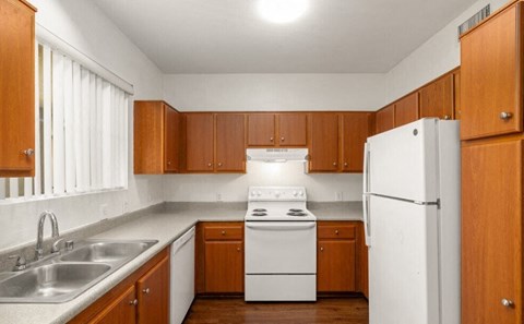A kitchen with white appliances and wooden cabinets.