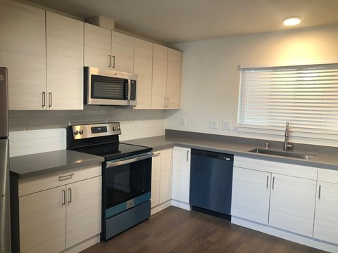 A kitchen with white cabinets and a black dishwasher.