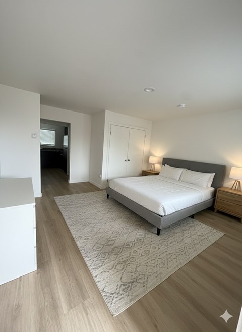 A bedroom with a large bed and a wooden floor.