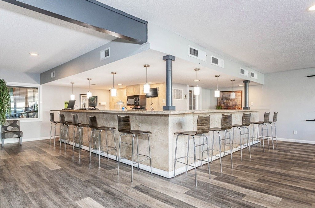 A bar area with a long counter and stools.