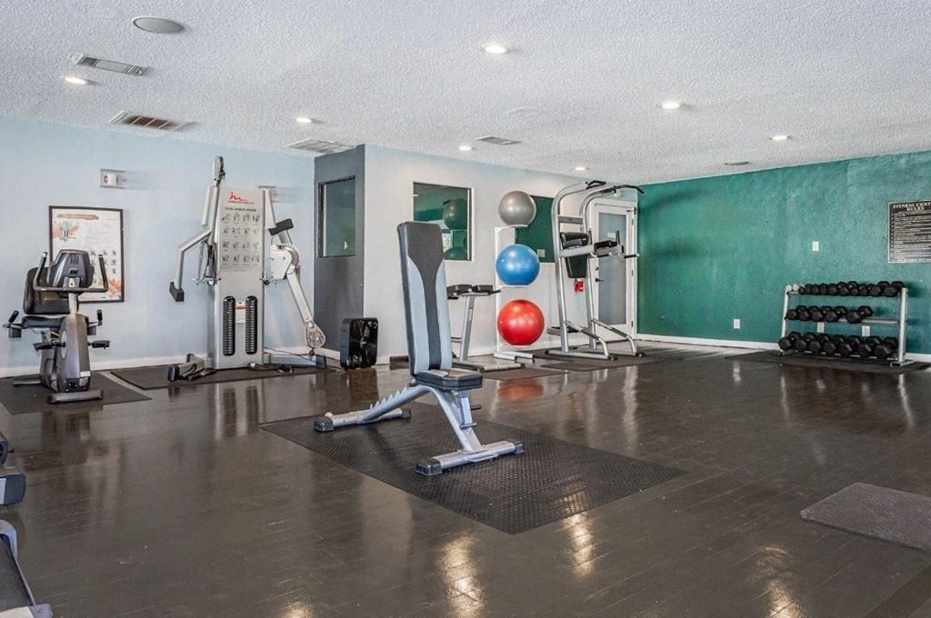 A gym with a variety of equipment including weights and exercise balls.