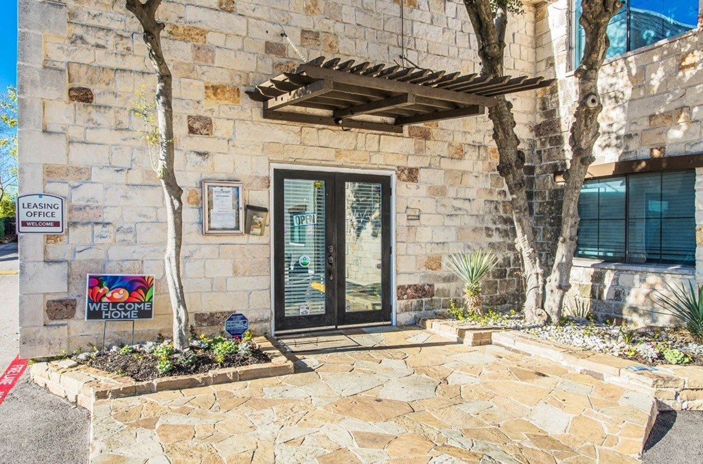 A stone building with a glass door and a leasing sign.