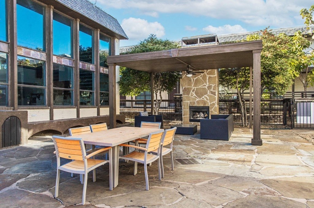 A patio with a table and chairs and a fireplace.