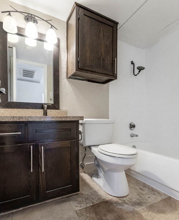 A white toilet sits in a bathroom with a wooden cabinet and a mirror above it.