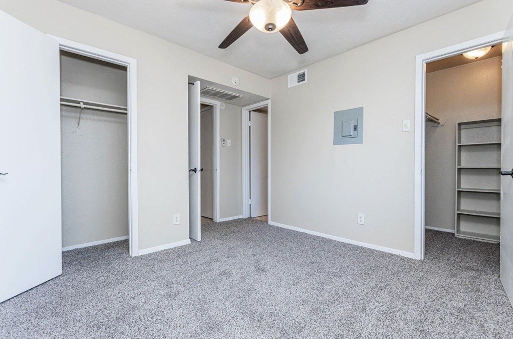 A room with a ceiling fan and a closet with shelves.