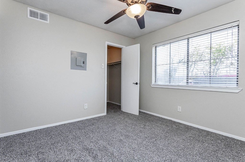 A room with a ceiling fan and a window with blinds.