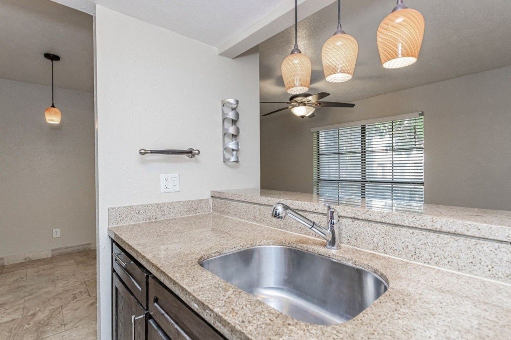 A modern bathroom with a granite countertop and a stainless steel sink.