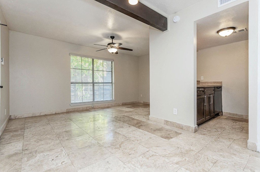 A spacious room with a ceiling fan and a window with blinds.