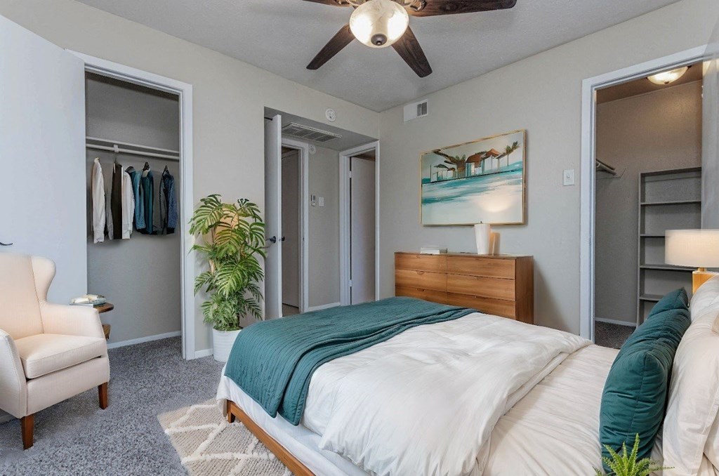 A bedroom with a bed, chair, and painting on the wall.