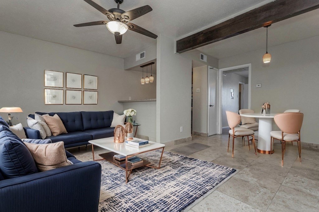 A living room with a blue sofa, a coffee table, and a ceiling fan.