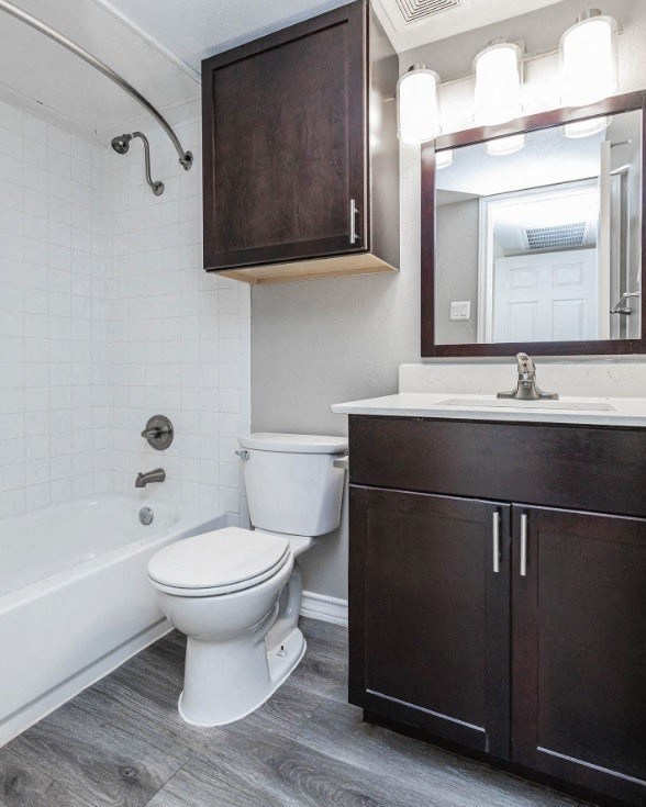 A white toilet sits in a bathroom next to a bathtub.