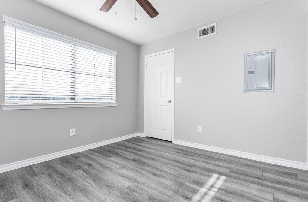 A room with a white door, a window with blinds, and a ceiling fan.