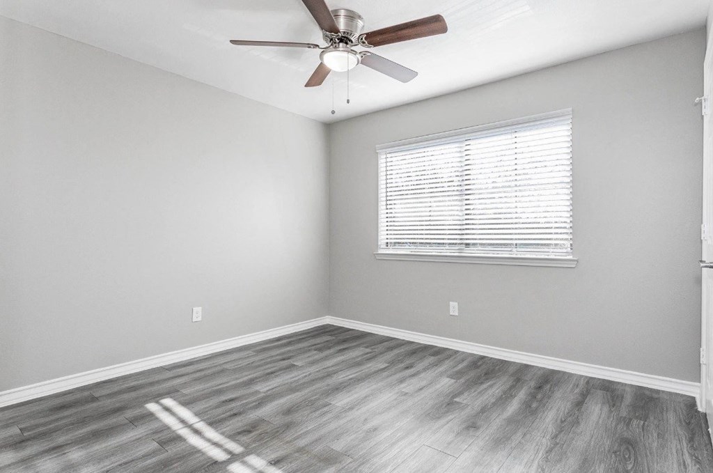 A room with a ceiling fan and a window with blinds.