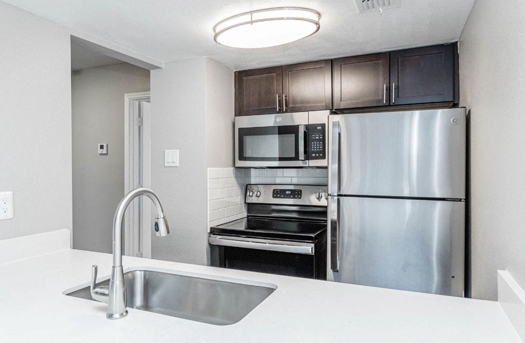 A kitchen with a stainless steel refrigerator, microwave, and oven.
