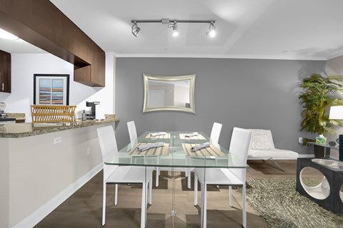 A modern dining room with a glass table and white chairs.