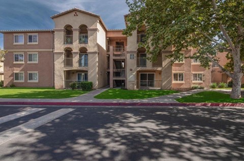 A large apartment building with a tree in front.