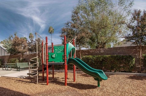 A playground with a green slide and a red frame.