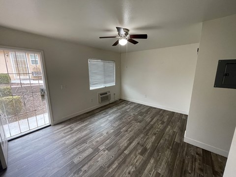 an empty living room with wood flooring and a ceiling fan
