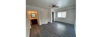 an empty living room with wooden floors and a ceiling fan