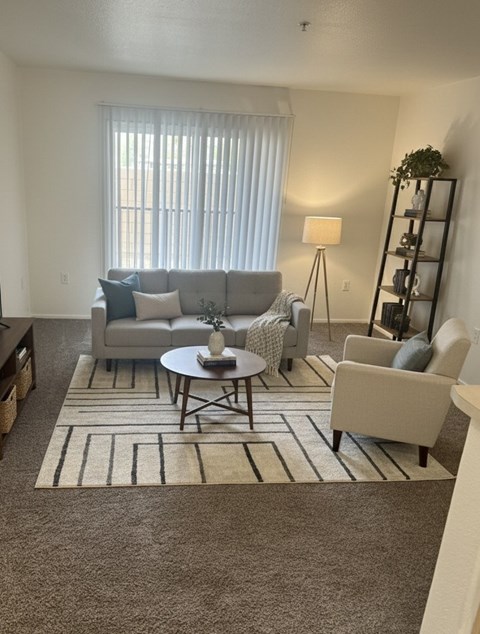 A living room with a grey couch, a white armchair, a coffee table, and a floor lamp.
