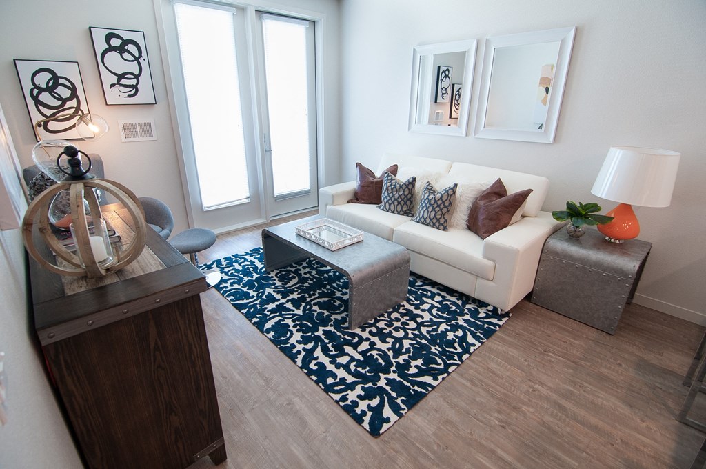 A living room with a white couch and a blue and white patterned rug.