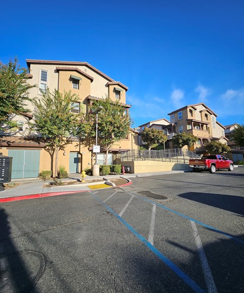 A parking lot with a red truck and apartment buildings in the background.