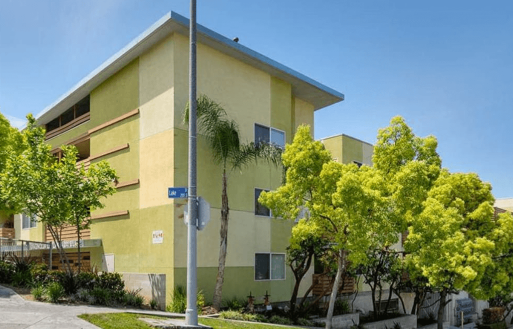 A street sign is on a pole in front of a yellow building.