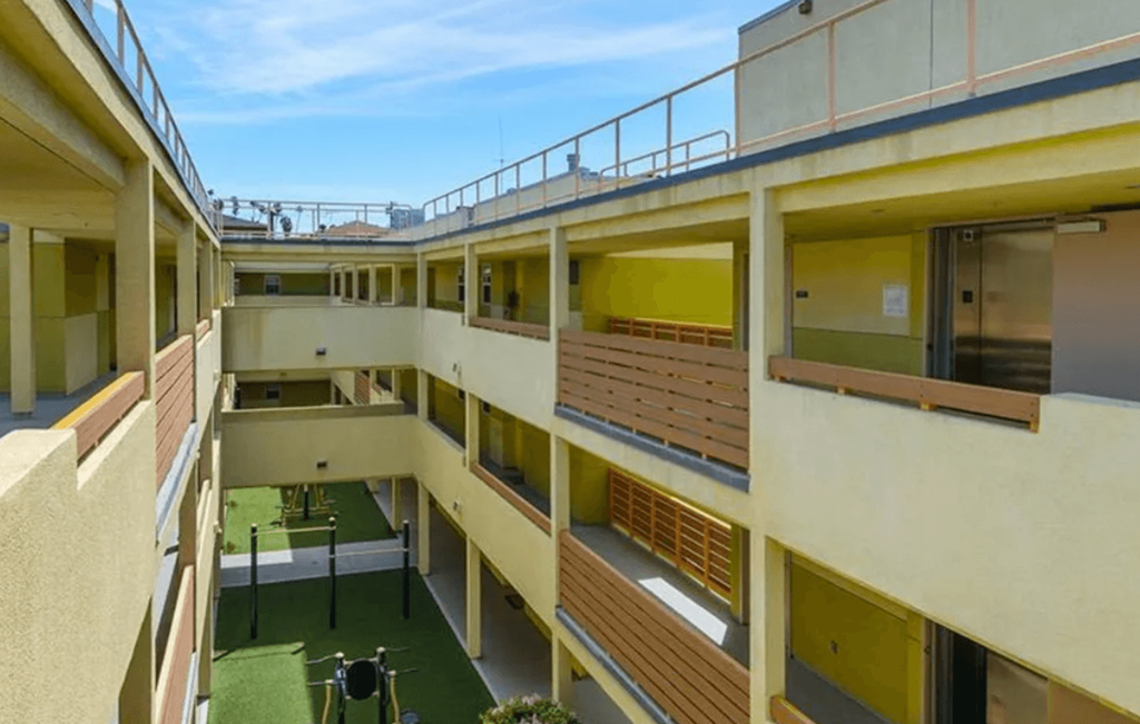 A view of a courtyard from a balcony with a green lawn and a drone.