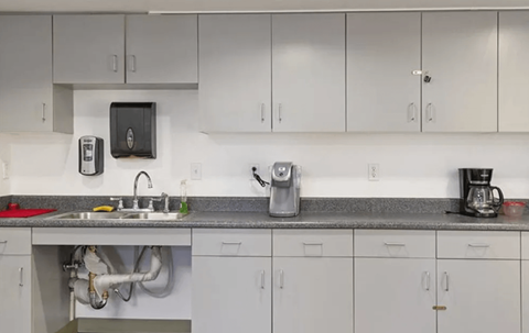 A kitchen with white cabinets and a grey countertop.