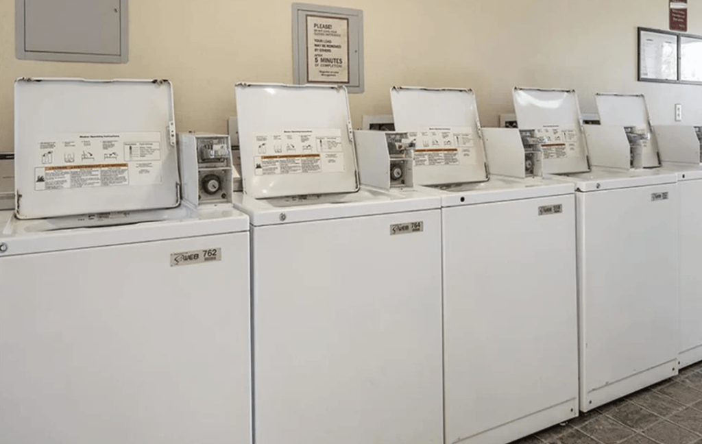 A row of washing machines are lined up in a laundromat.