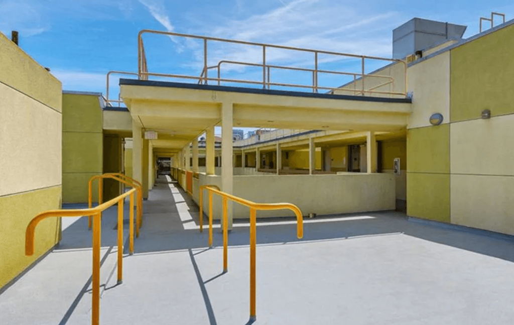 A yellow building with a metal railing and orange handrails.