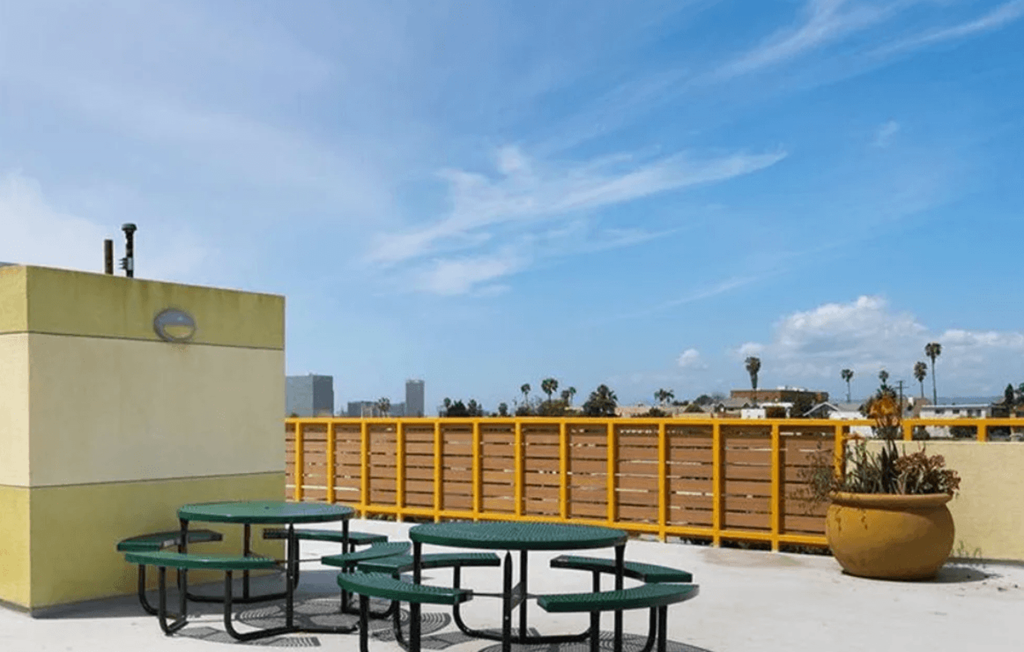 A yellow building with a green table and chairs in front of it.