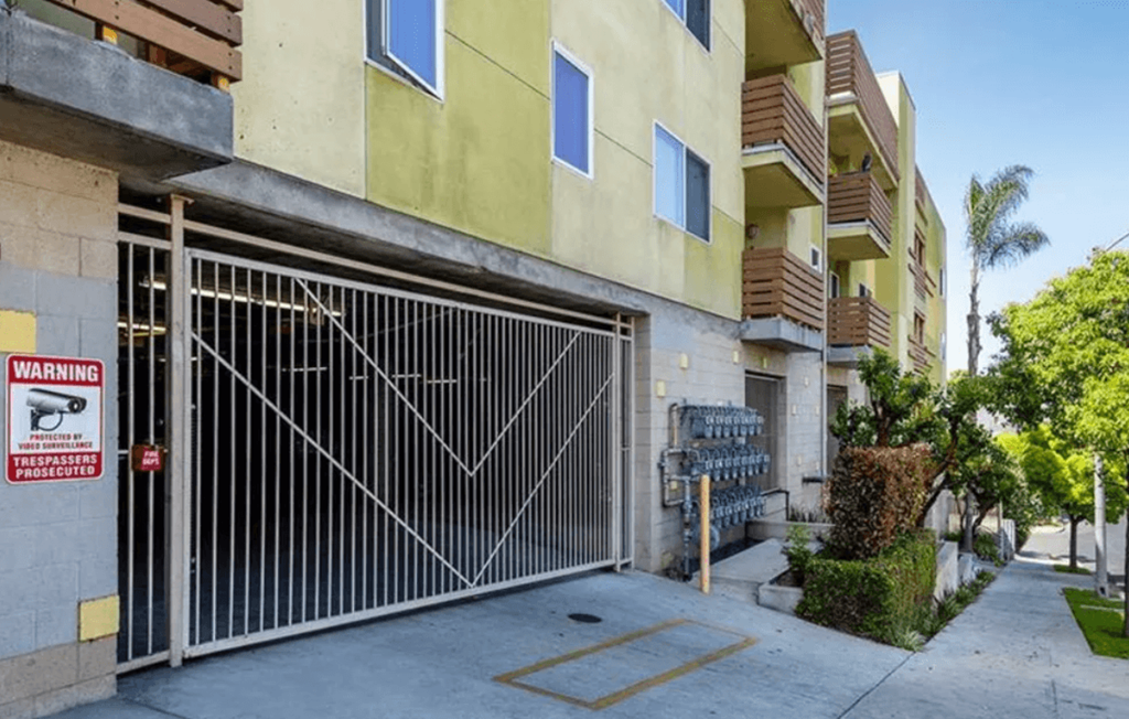 A gated entrance to a residential building with a warning sign.