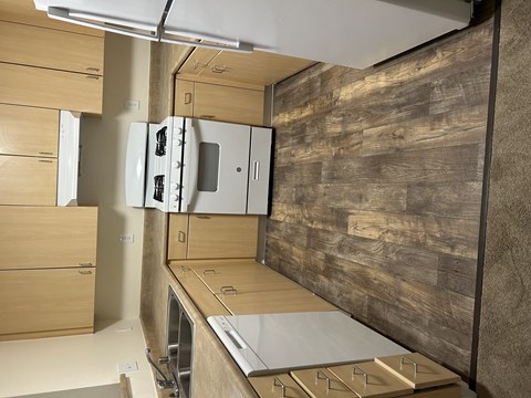 A kitchen with a refrigerator, oven, and wooden cabinets.