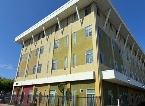 A multi-story building with a yellow and green facade and a red door on the ground floor.