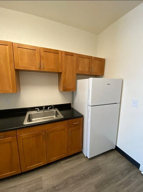 A kitchen with a white refrigerator and wooden cabinets.