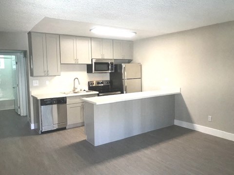 an empty kitchen with white cabinets and stainless steel appliances