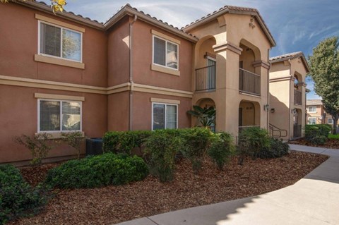 A building with a red stucco exterior and a landscaped front yard.