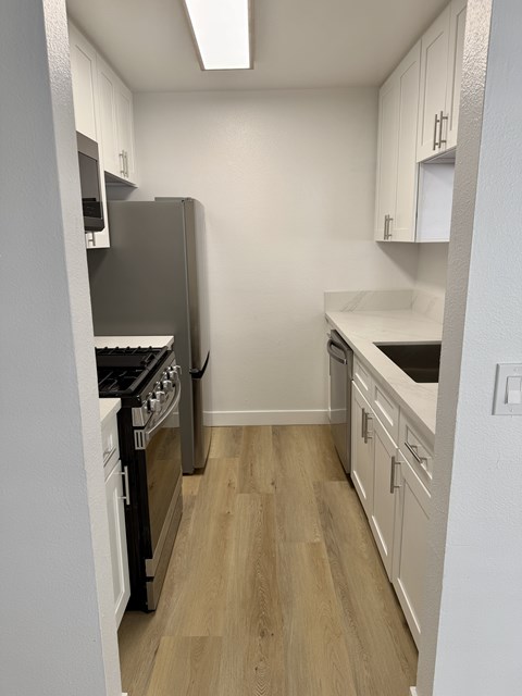 A kitchen with a refrigerator, oven, and cabinets.
