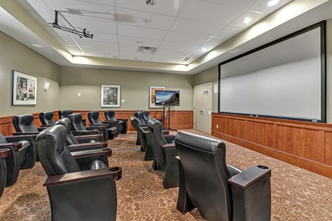 a large conference room with leather chairs and a projector screen