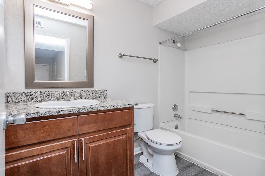 A bathroom with a toilet, sink, and mirror.